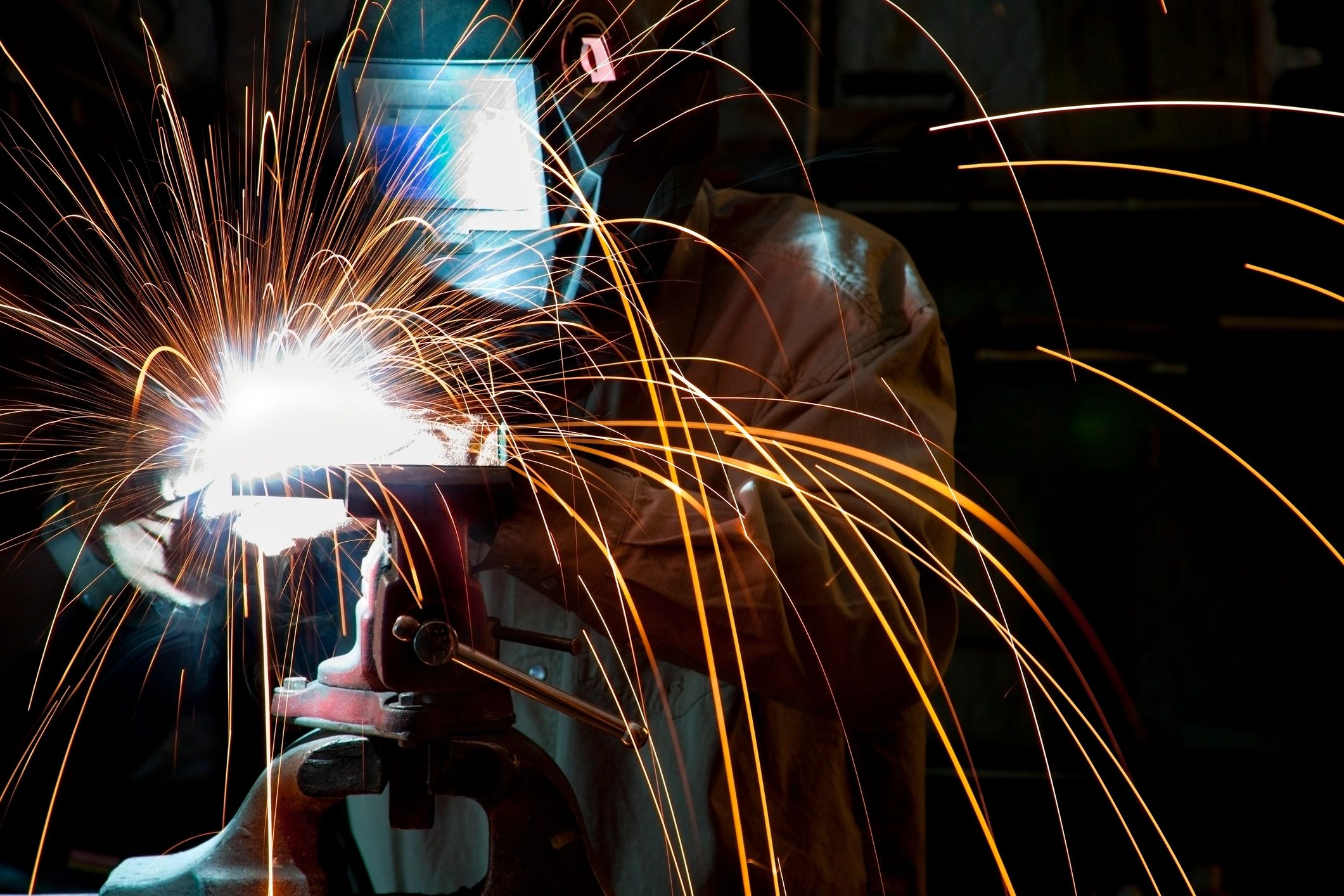 Welder in a steel fabrication shop with sparks flying