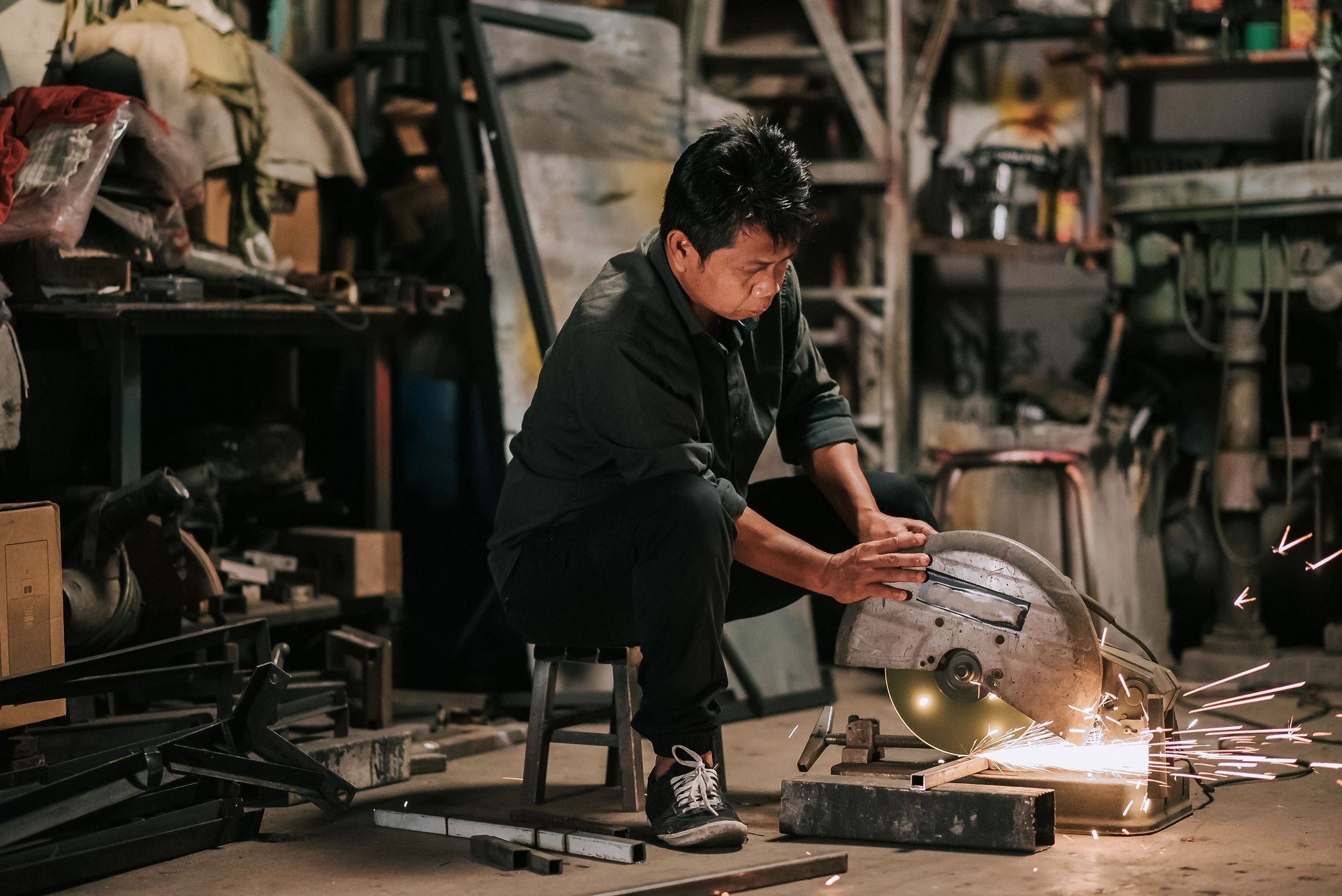 Metalworker cutting steel with an angle grinder in a fabrication workshop