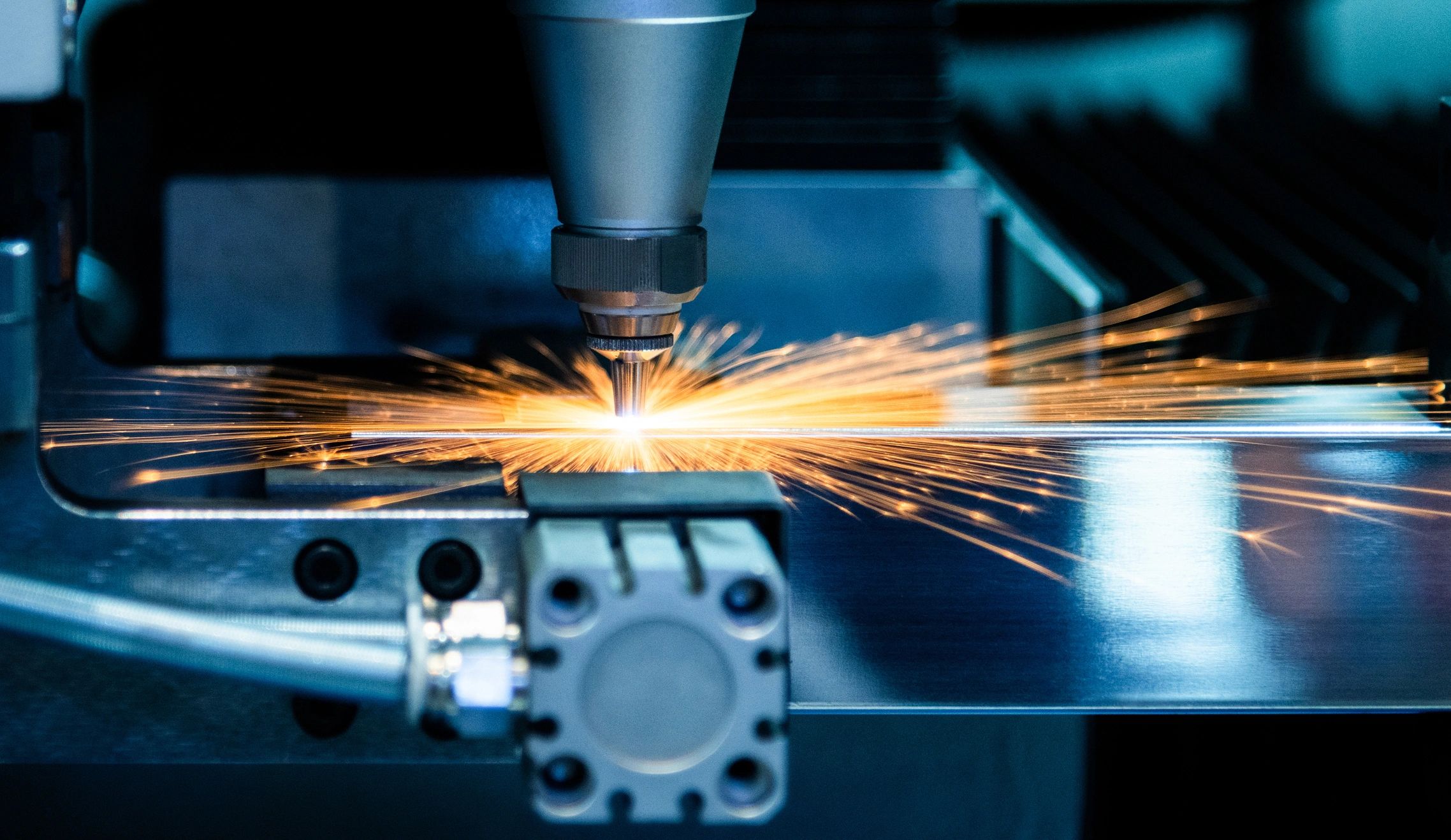 CNC laser cutting a steel sheet with sparks flying
